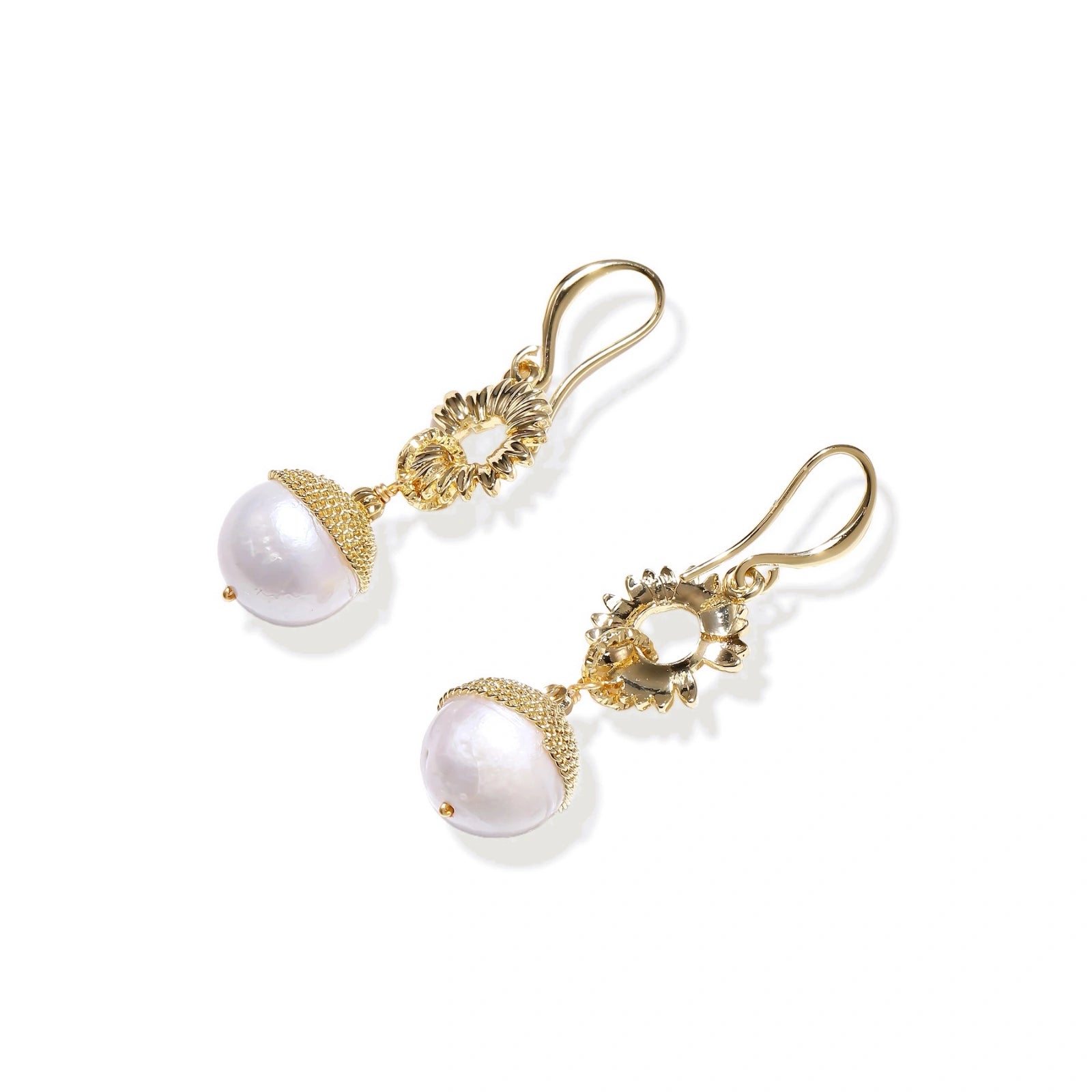 Gold sunburst charm earrings with baroque pearl drops on French hooks against cream background