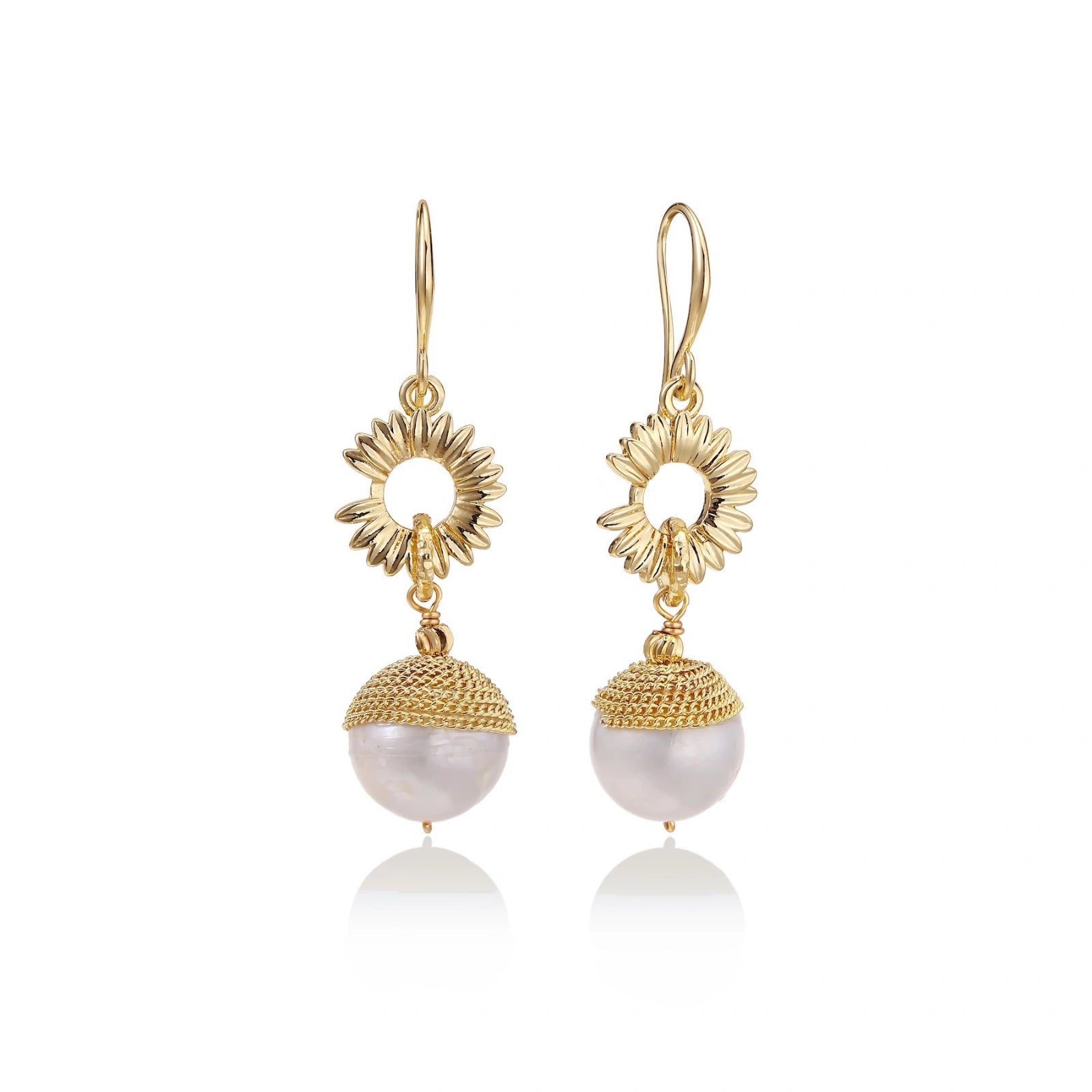 Gold sunburst charm earrings with baroque pearl drops on French hooks against cream background