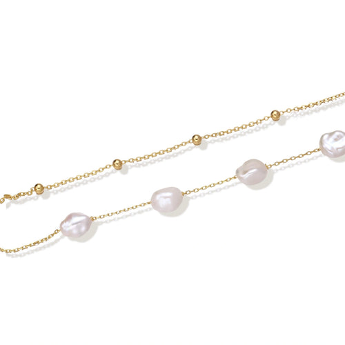 Double-strand gold bracelet with irregular baroque pearls and smooth freshwater pearls on cream background.
