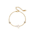 Gold chain bracelet with white mother of pearl butterfly pendant and two bezel-set crystals on cream background