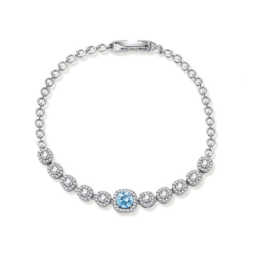 Sterling silver tennis bracelet with round halo-set moissanite stones and blue center stone on cream background.