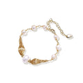 Adjustable gold bracelet with freshwater pearls and textured filigree beads on white background, showing clasp detail.