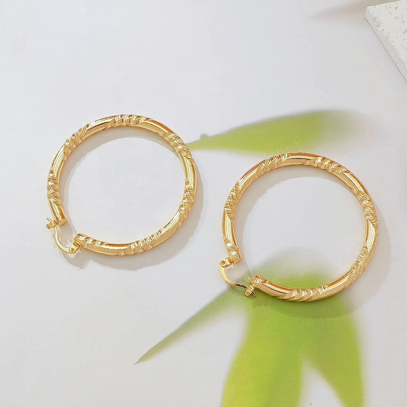 Twisted Gold Huggie Hoops — faceted diamond-cut huggie hoop earrings