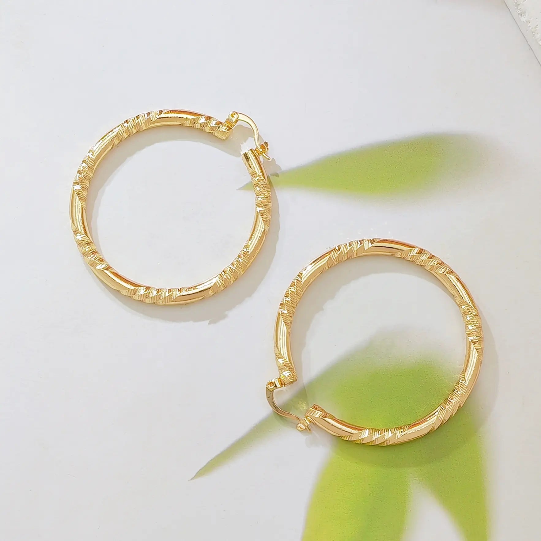 Twisted Gold Huggie Hoops — faceted diamond-cut huggie hoop earrings