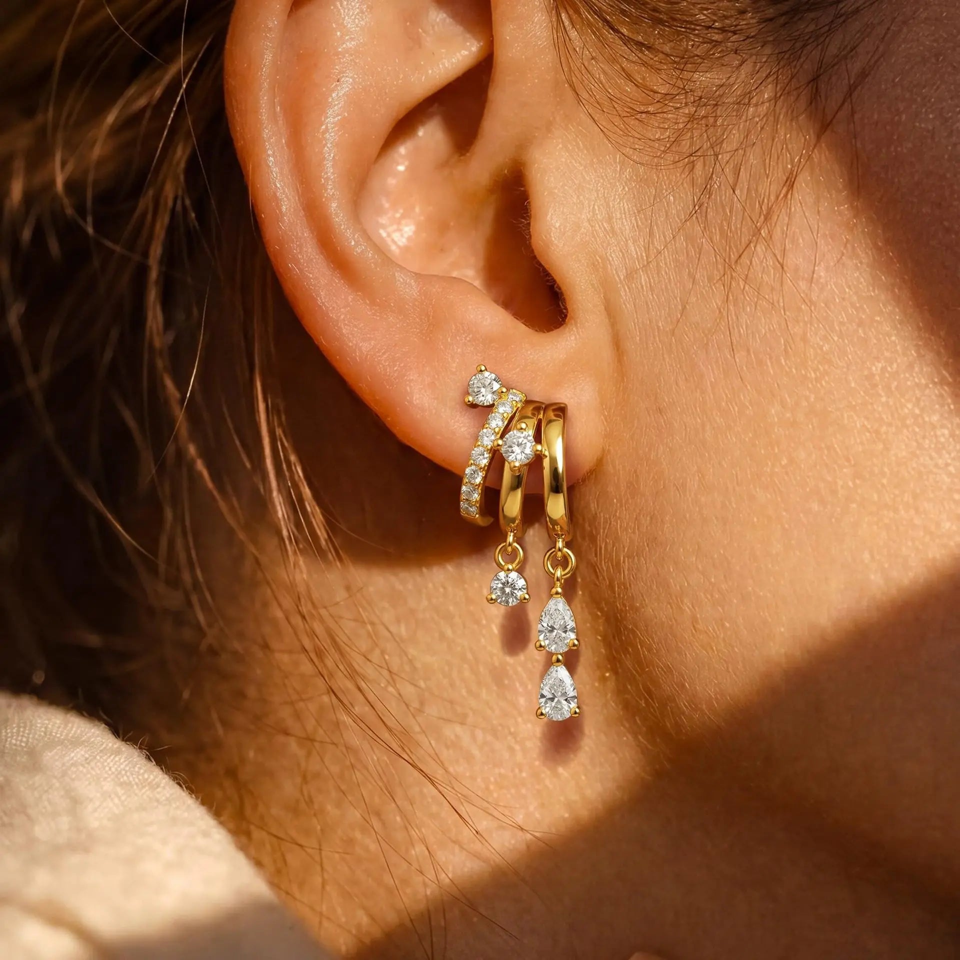 Triple Stack Huggie Earrings — three-tier huggie hoops with cubic zirconia drops